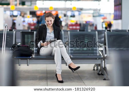 Young female passenger at the airport using her tablet computer while waiting for her flight Young female passenger at the airport using her tablet computer while waiting for her flight