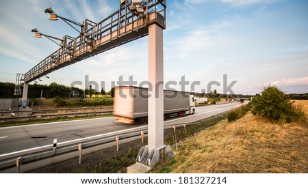 truck passing through a toll gate on a highway (motion blurred image; color toned image)