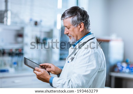 Senior doctor using his tablet computer at work (color toned image)