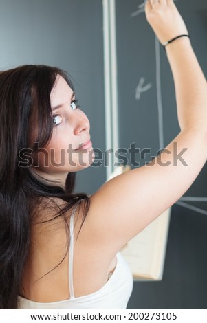 Pretty, young college student drawing on the chalkboard/blackboard during a math class (shallow DOF; color toned image)