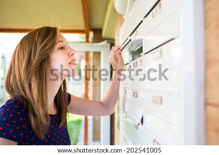 Pretty, young woman checking her mailbox for new letters