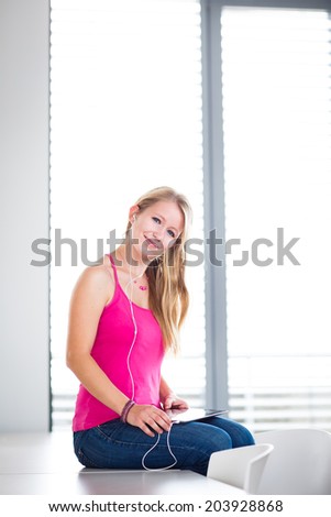 Pretty, young female student listening to music on her tablet computer (color toned image)