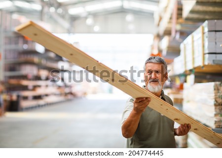 Man choosing and buying construction wood in a  DIY store for his DIY home re-modeling project