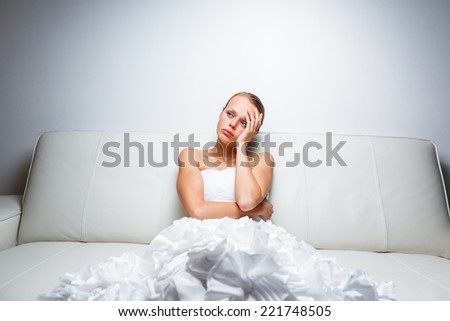 Sad bride crying, sitting on a sofa, smitten, feeling low and depressed