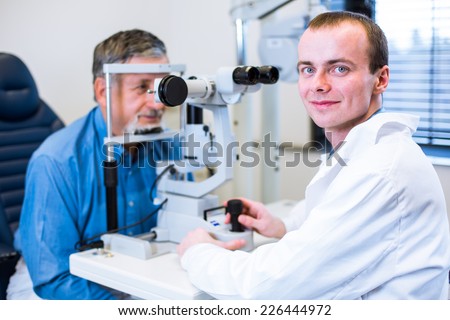 Optometry concept - senior man having his eyes examined by an eye doctor (color toned image; shallow DOF)