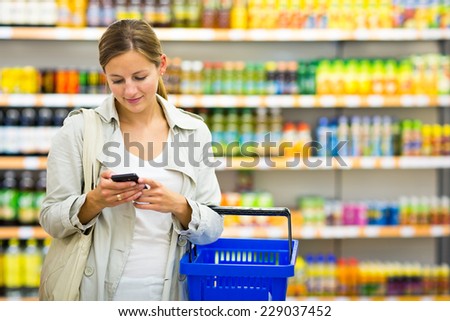 Pretty young woman buying groceries in a supermarket/mall/grocery store (color toned image; shallow DOF)