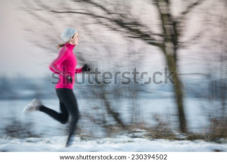 Young woman running outdoors on a cold winter day (motion blurred image)