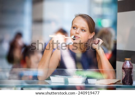 Pretty, young woman eating sushi in a restaurant, having her lunch break, enjoying the food, pausing for a while from her busy corporate/office life (color toned image)