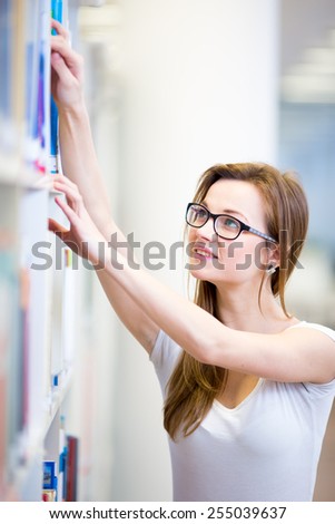 Pretty, female college student in a library, looking for a book (shallow DOF; color toned image)