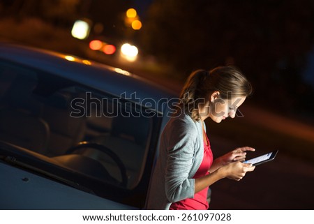 Pretty, female driver using her tablet computer (shallow DOF; color toned image)