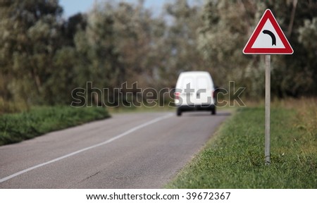 White pick-up going on a contryside road with a sharp corner sign on a lovely day