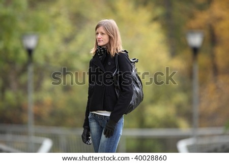 Portrait of a pretty young woman standing in a park on a lovely autumn day