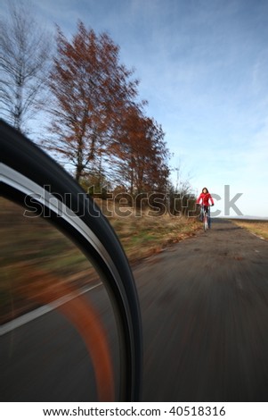 Biking (the image is motion blurred to convey movement; focus is on the wheel, the female biker is left out of focus)