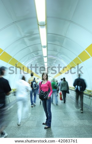 Subway - young woman standing in a subway corridor while the crowd of commuters passes by