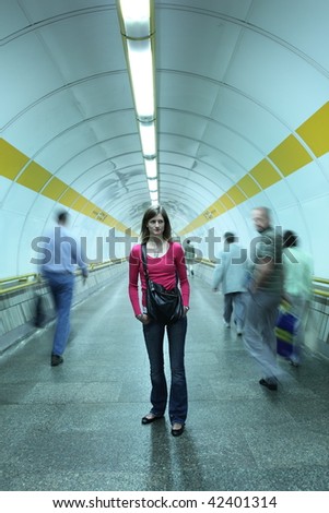 Subway - young woman standing in a subway corridor while the crowd of commuters passes by