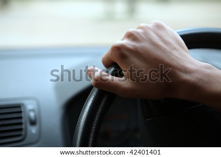 Close-up of a male hand on steering wheel in a modern car in the UK (steering wheel on the right)