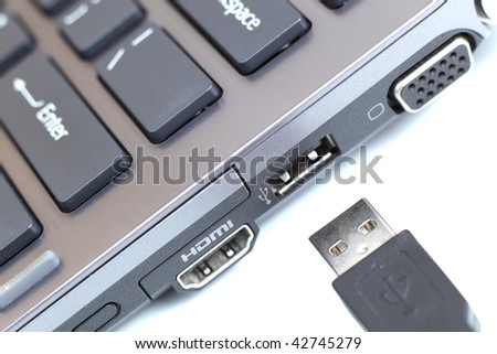 modern hi-end carbon laptop computer with great connectivity and a USB cable on white background