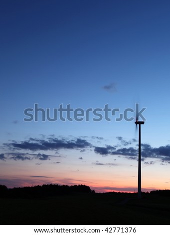 Wind power - turning wind turbine in front of a lovely sky at dusk