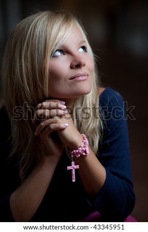 Beautiful young woman with a rosary/prayer beads praying to God