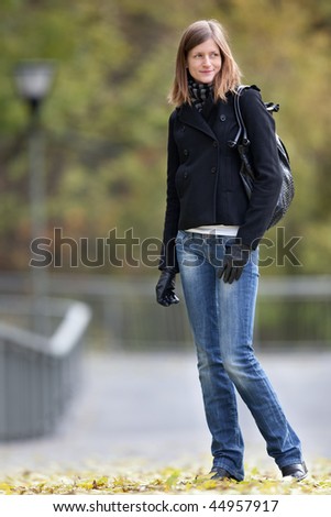 Portrait of a pretty young woman standing in a park on a lovely autumn day
