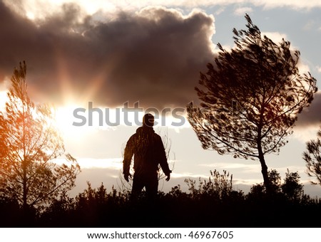 facing the dusk - young man's silhouette against dramatic sky with clouds and late evening sunshine