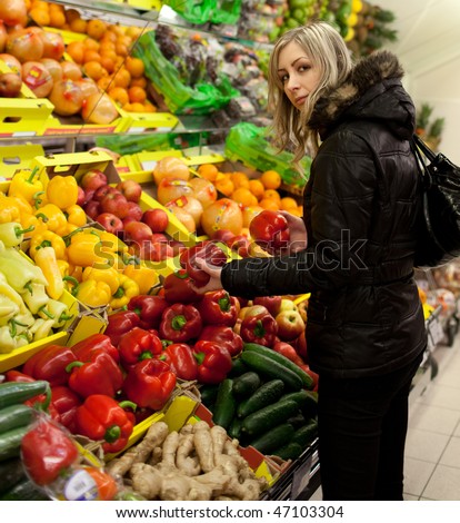 Beautiful young woman shopping for fruits and vegetables at a supermarket