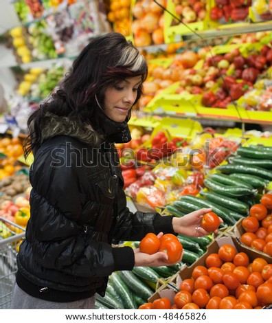 Beautiful young woman buying fruits and vegetables at a supermarket/grocery