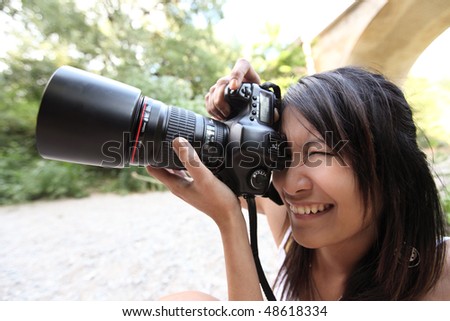 pretty female photographer taking photos with her modern DSLR camera