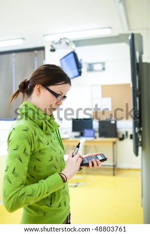 young female college student in front of a whiteboard using a calculator during math class