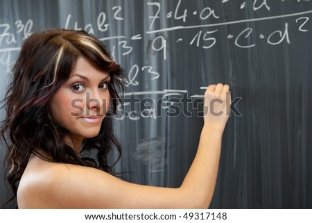 pretty young college student writing on the chalkboard/blackboard during a math class