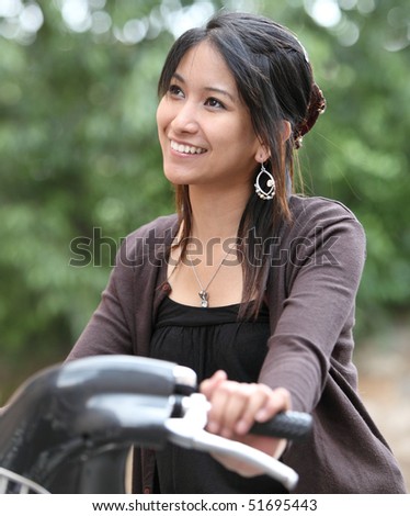 Verry pretty young asian woman on bike smiling while commuting/biking to work