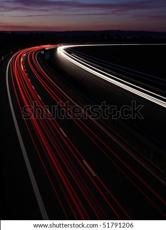 Cars in a rush moving fast on a highway (speedway) at dusk