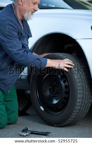 mechanic changing a wheel of a modern car (color toned image)
