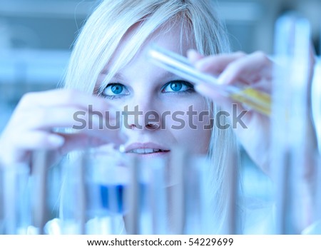 Closeup of a female researcher holding up a test tube and a retort and carrying out experiments (color toned image)