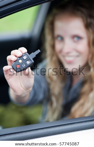 Pretty young woman showing off her brand new car - showing you the car keys