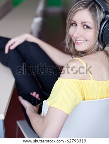 Beautiful young woman listening to music on hi-end hi-fi headphones (shallow DOF; focus on the left eye; color toned image)