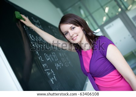 pretty young college student writing on the chalkboard/blackboard during a math class (color toned image)