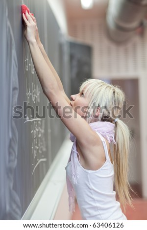 pretty young college student erasing the chalkboard/blackboard during a math class (color toned image)