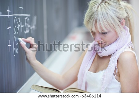 pretty young college student writing on the chalkboard/blackboard during a math class (color toned image)