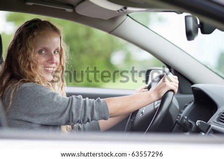 Pretty young woman driving her new car (color toned image)