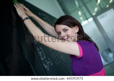 pretty young college student or teacher writing on the chalkboard/blackboard during a math class (shallow DOF; color toned image)