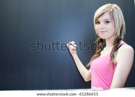 pretty young college student writing on the chalkboard/blackboard during a math class (shallow DOF; color toned image)