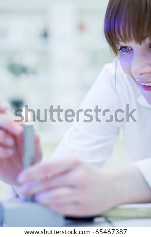 pretty, young female researcher lighting up a burner in a lab (shallow DOF; color toned image)
