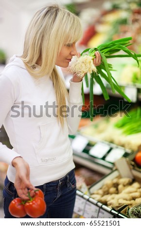 Beautiful young woman shopping for fruits and vegetables in produce department of a grocery store/supermarket (shallow DOF; color toned image)