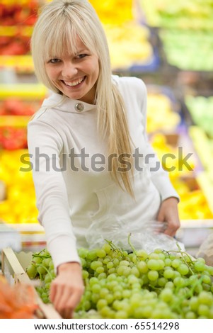 Beautiful young woman shopping for fruits and vegetables in produce department of a grocery store/supermarket (color toned image; shallow DOF)