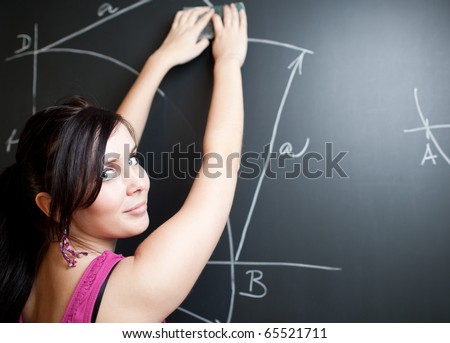 pretty young college student drawing on the chalkboard/blackboard during a math class (shallow DOF; color toned image)