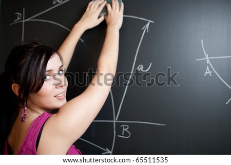 pretty young teacher/college student drawing on the chalkboard/blackboard during a math class (shallow DOF; color toned image)