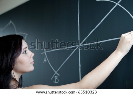 pretty young teacher drawing on the chalkboard/blackboard during a math class (shallow DOF; color toned image)