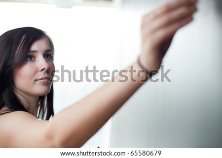 pretty young teacher/college student drawing on the chalkboard/blackboard during a math class (shallow DOF; color toned image)