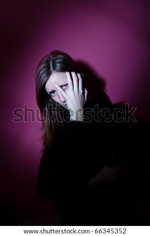 Young woman suffering from a severe depression/anxiety (color toned image; harsh lighting is used to convey the mood of unease)